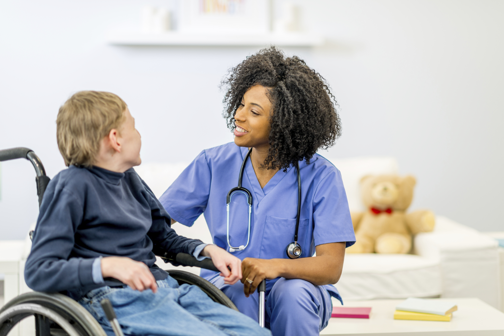 Pediatric nurse giving compassionate in-home healthcare services to a child in a wheelchair